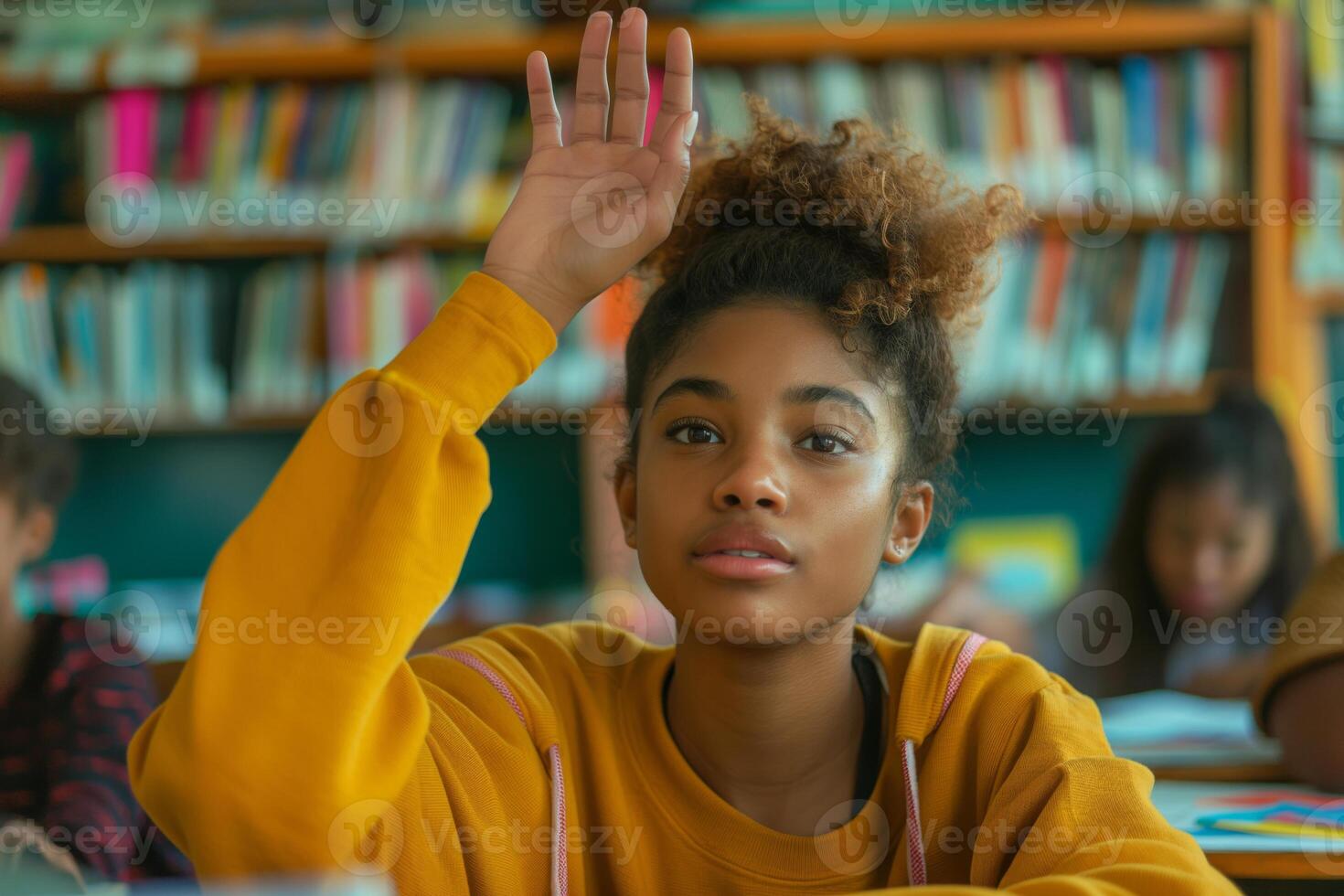 A female student with curly hair raises her hand in a vibrant classroom, showcasing her eagerness to participate in the lesson. photo