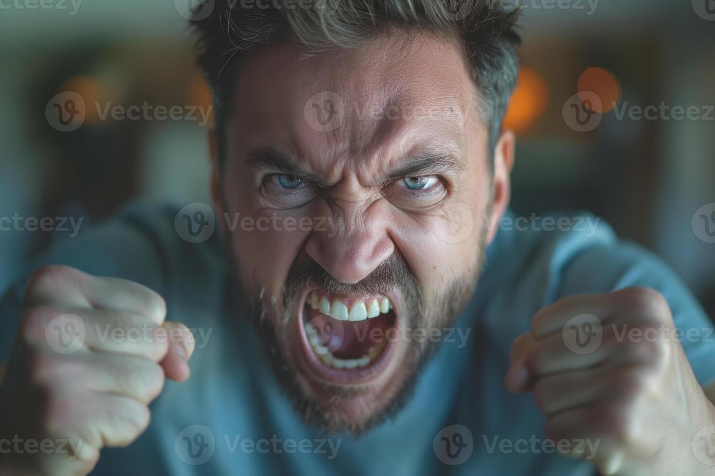 A male with light brown hair expresses intense anger, his face showing fury with clenched fists and a fierce scream. photo