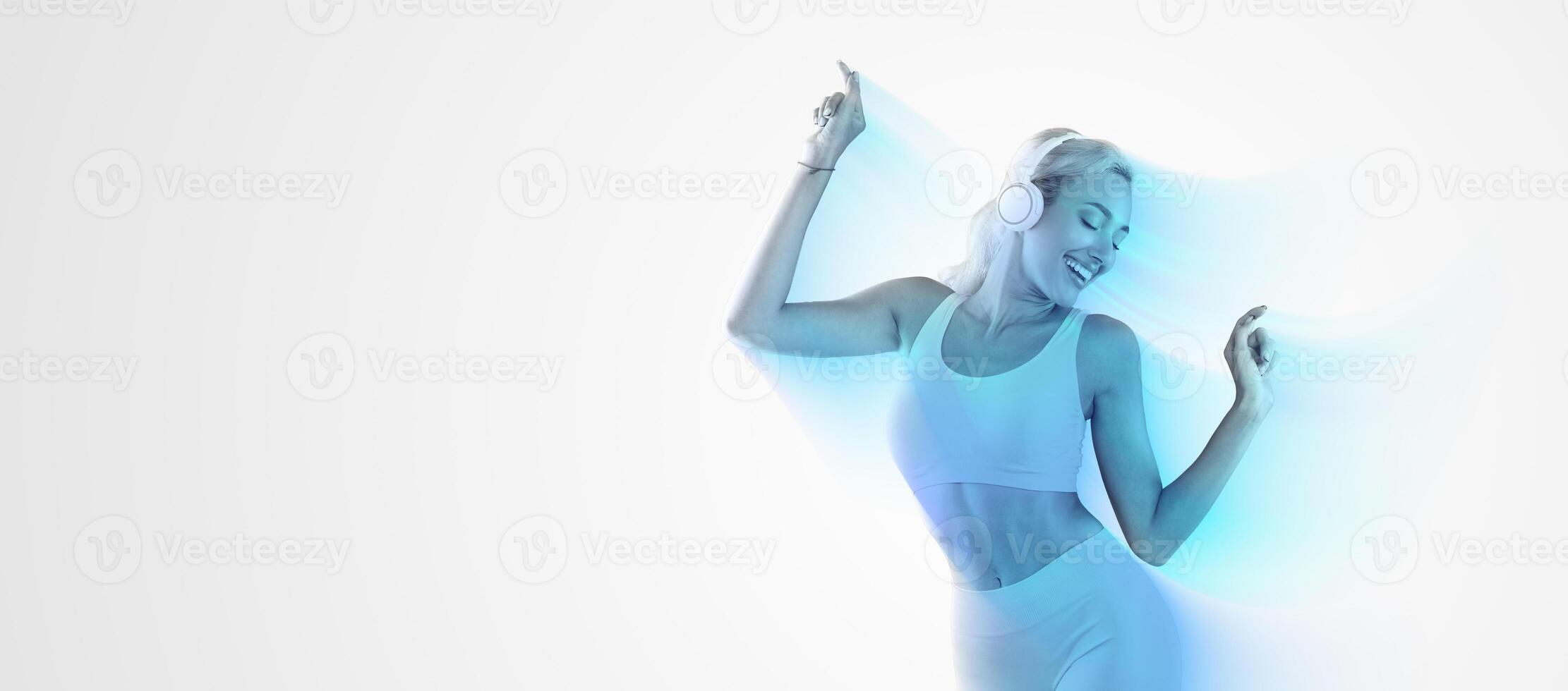 Favorite Song. Portrait Of Excited Young Sportive Lady Wearing Wireless Headset Listening To Music And Dancing Isolated Over Blue Studio Background. Fit Lady With Closed Eyes Enjoying Playlist photo