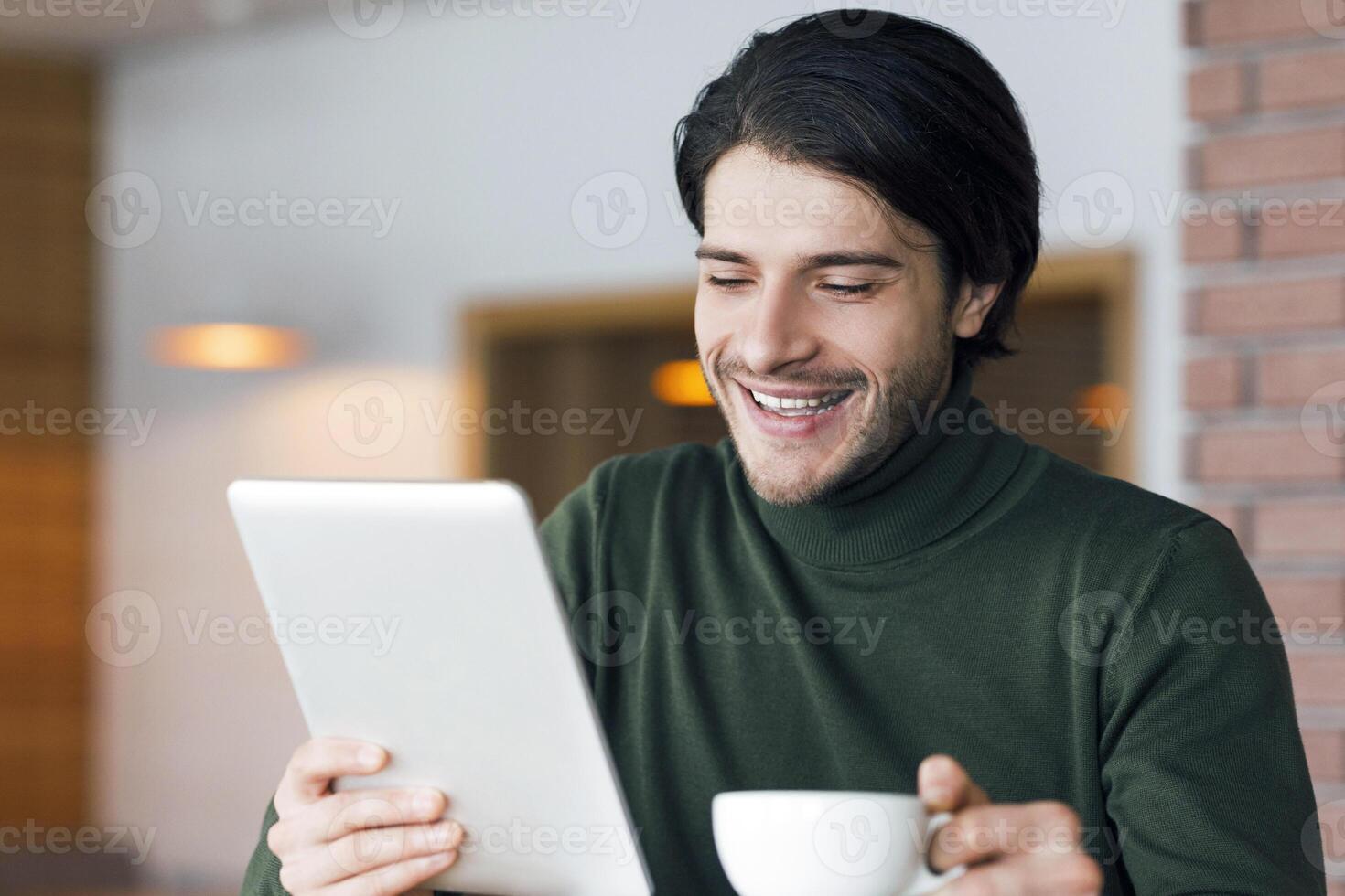 Freelancer having morning coffee at cafe, checking news online on digital tablet, copy space photo