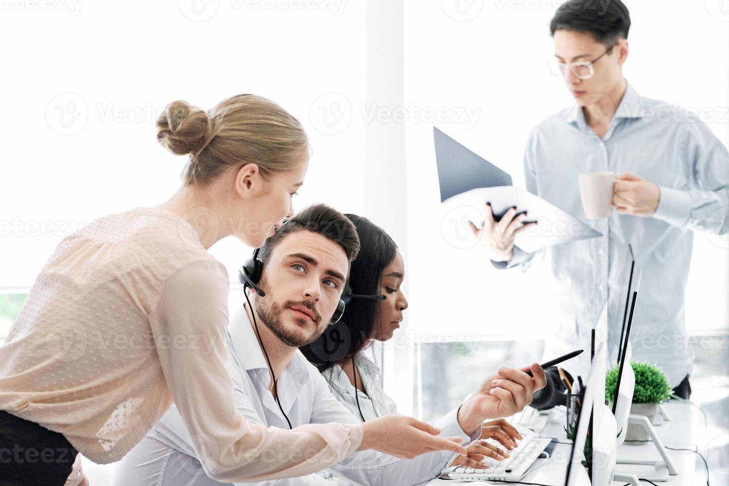Team of call centre operators at work in open space office photo