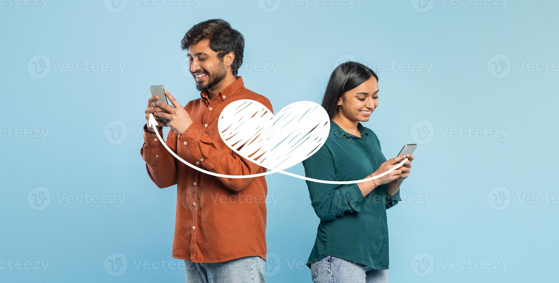 A couple stands back to back, smiling and engaged with their smartphones. They share affectionate messages using a messaging app, celebrating their love on St. Valentine's Day. photo