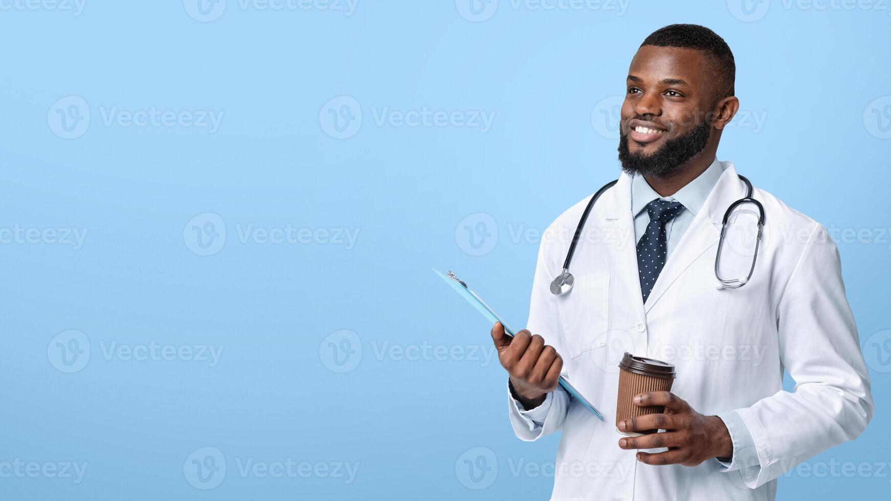 Cheerful african american male doctor with medical chart and cup of coffee looking at copy space over white background, panorama photo