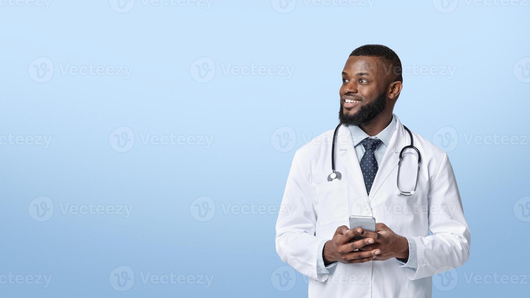 Call your doctor during quarantine. Happy african doctor with mobile phone looking at empty space over white studio background, panorama photo