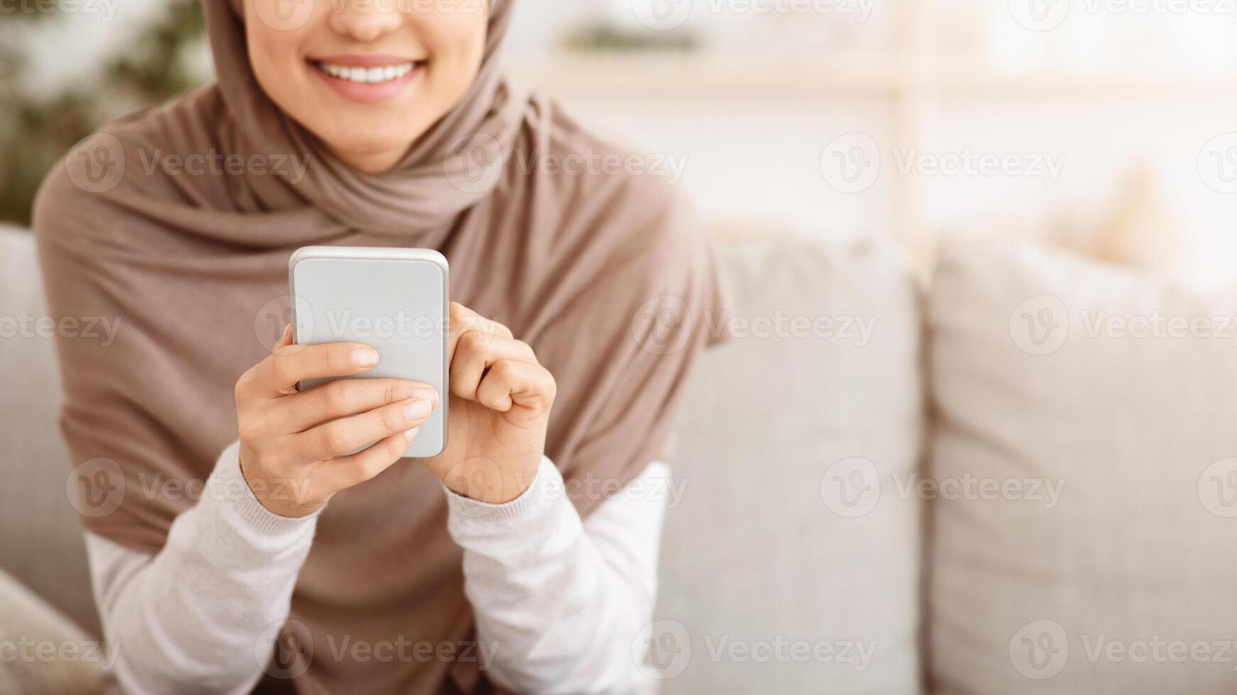 Modern Communication. Closeup Of Unrecognizable Muslim Woman In Hijab Using Smartphone At Home, Browsing Internet Or Texting With Friends, Panorama photo
