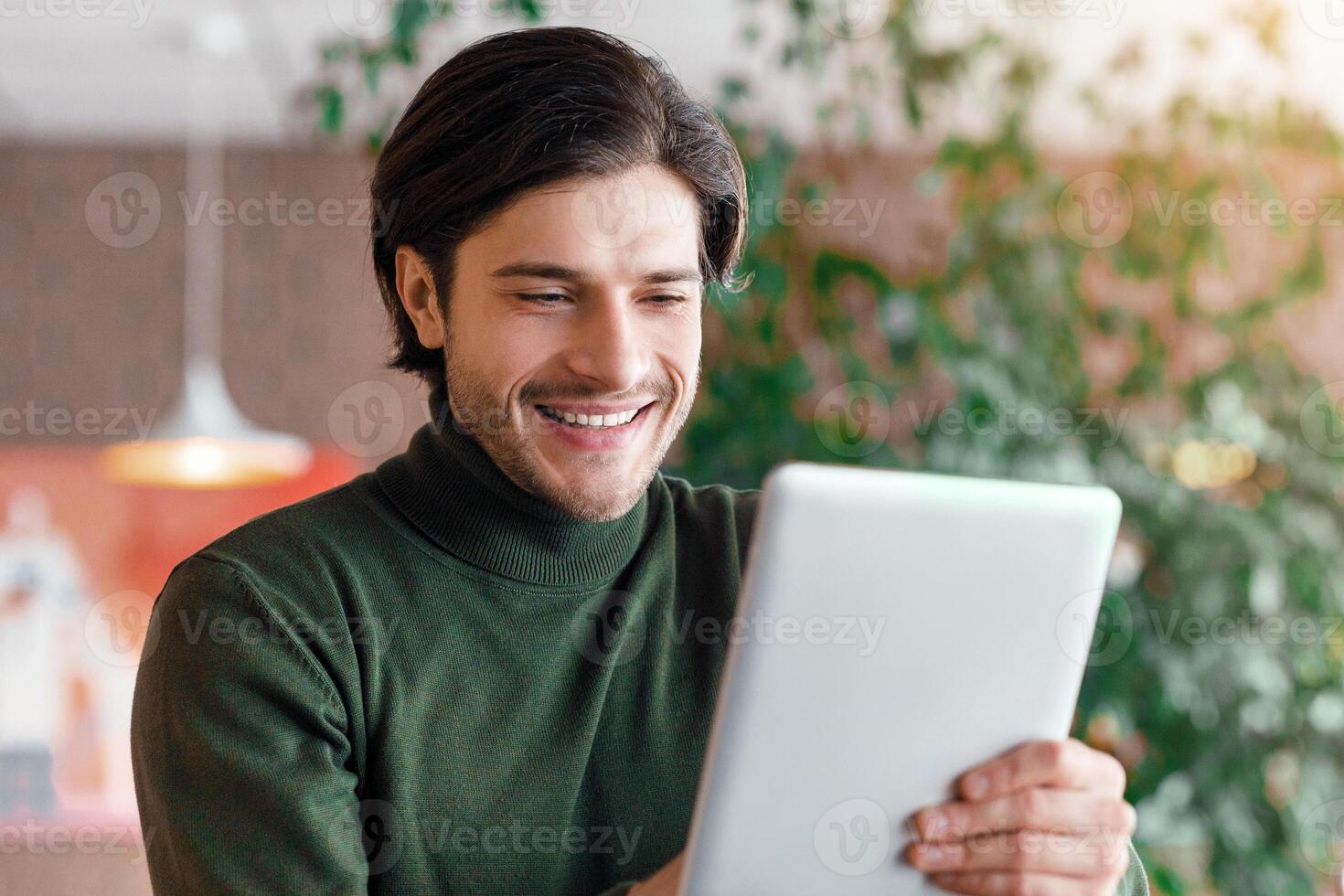 Cheerful man making call via digital tablet, having business conference, cafe interior, empty space photo