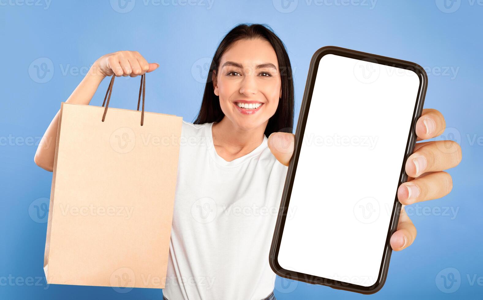 Portrait of casual caucasian woman taking selfie with shopping bag over turquoise studio wall, mock up, copyspace photo