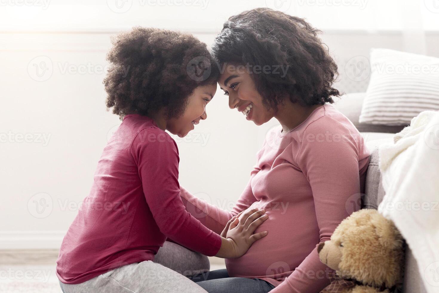 Waiting For Second Baby. Side View Portrait Of Happy Pregnant Black Woman And Her Little Daughter Bonding Together At Home, Copy Space photo