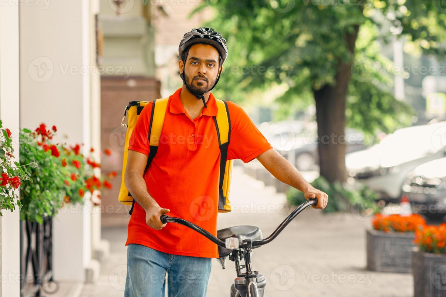 Bike, city and food delivery concept. Courier with beard, in helmet and bag, walks with bicycle to client, down the street, panorama, copy space photo