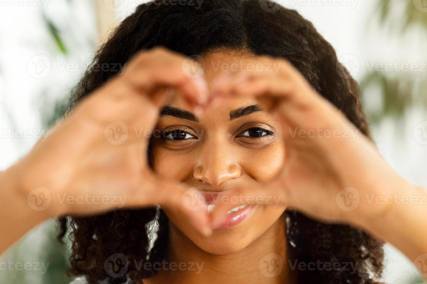 I Love Myself. Happy Black Woman Showing Heart Gesture With Fingers And Looking Through It, Closeup Shot With Copy Space photo