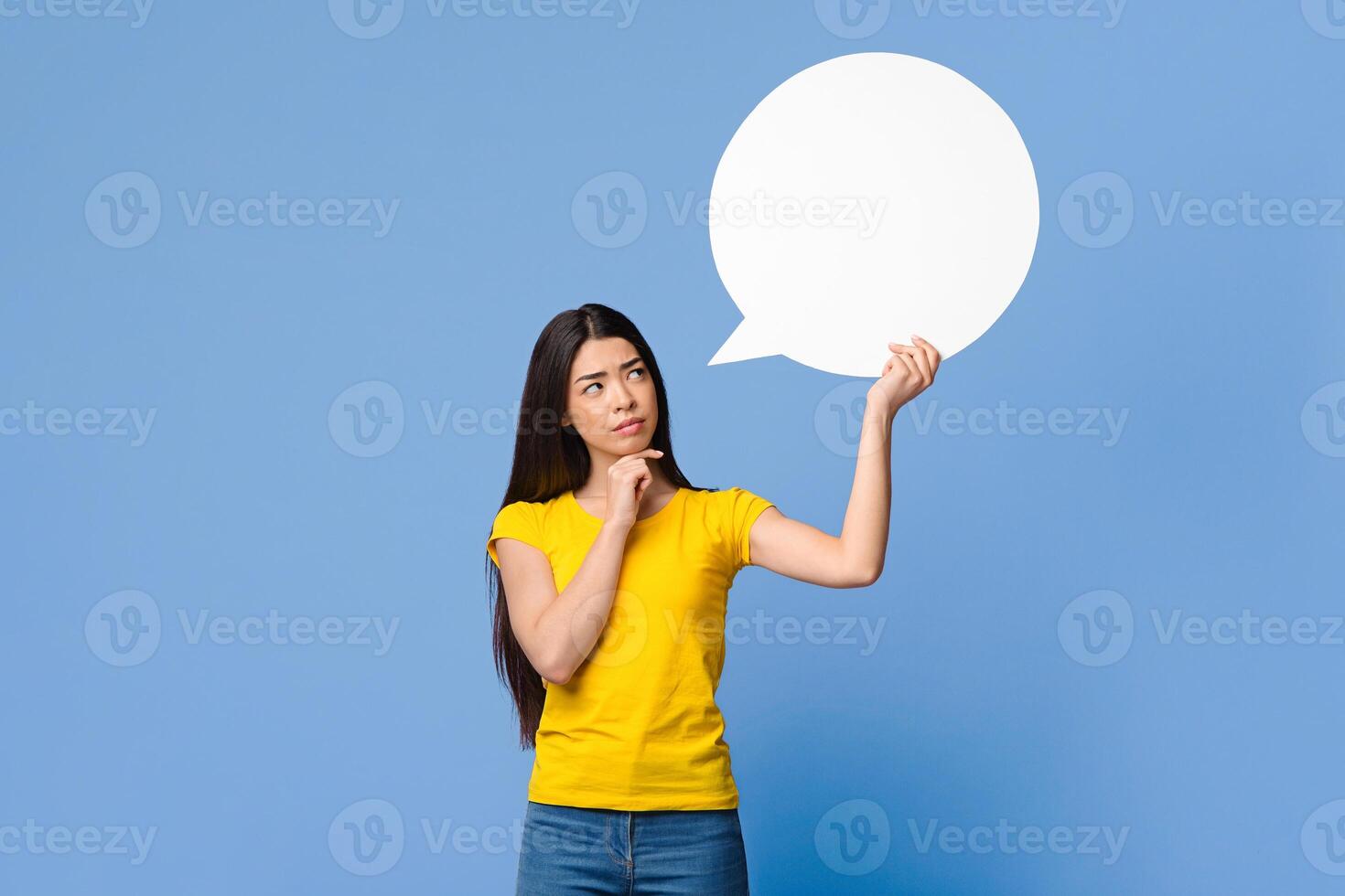 Let Me Think About It. Doubtful Asian Girl Holding And Looking At Empty Speech Bubble, Having Difficult Choice, Standing Over Purple Background photo