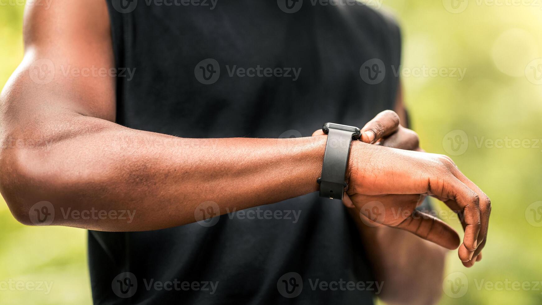 Cropped of black sportsman using his smartwatch while training at park, free space photo