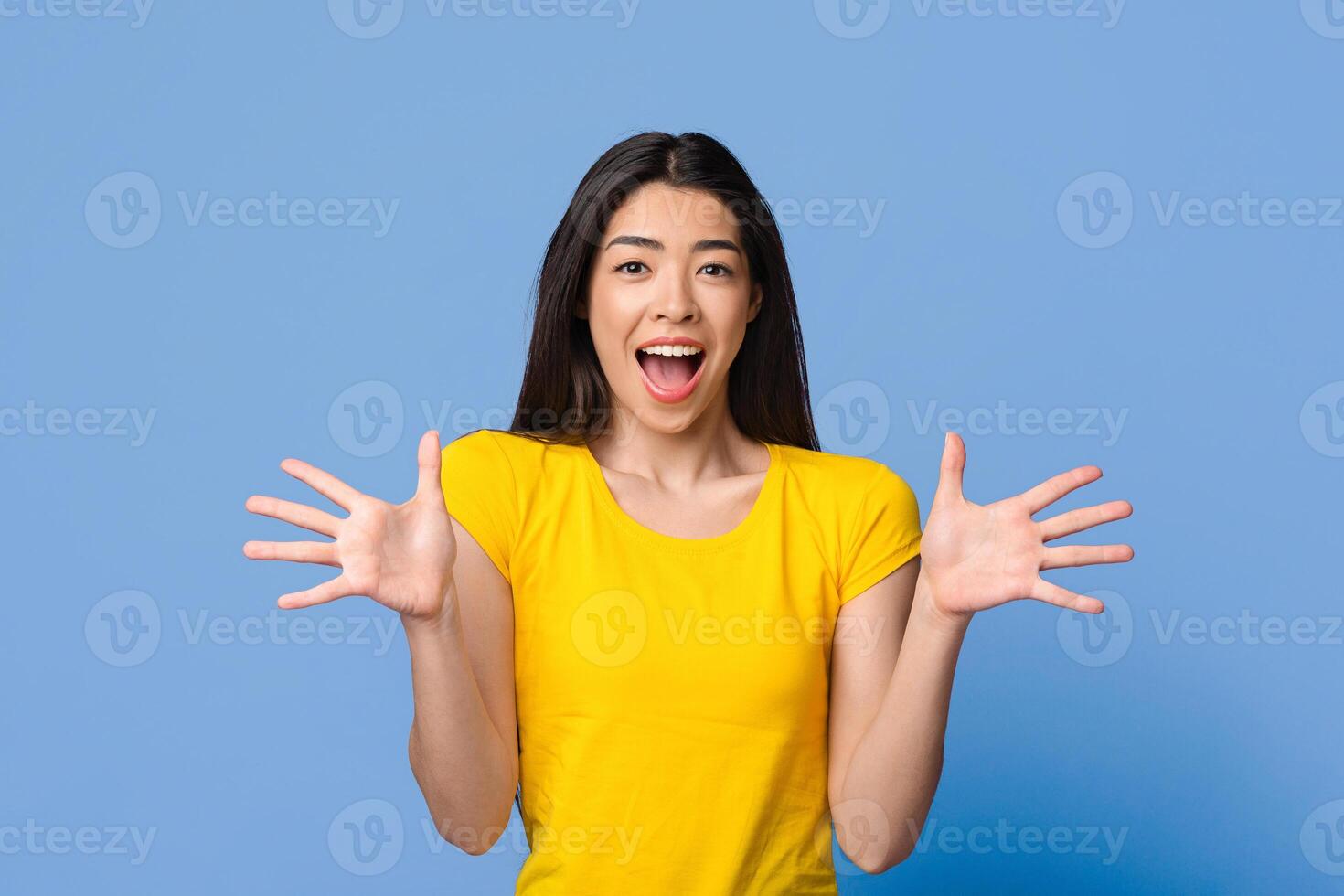Amazing Offer. Surprised asian woman with opened mouth spreading arms with excitement, looking at camera over purple studio background, copy space photo