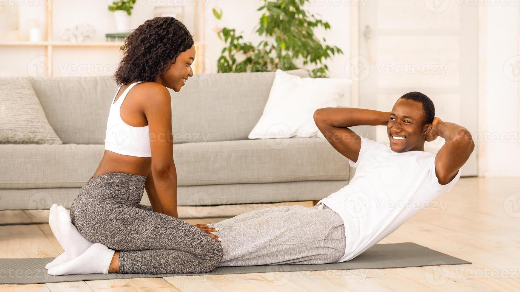 Young black couple exercising together at home, working on abs photo