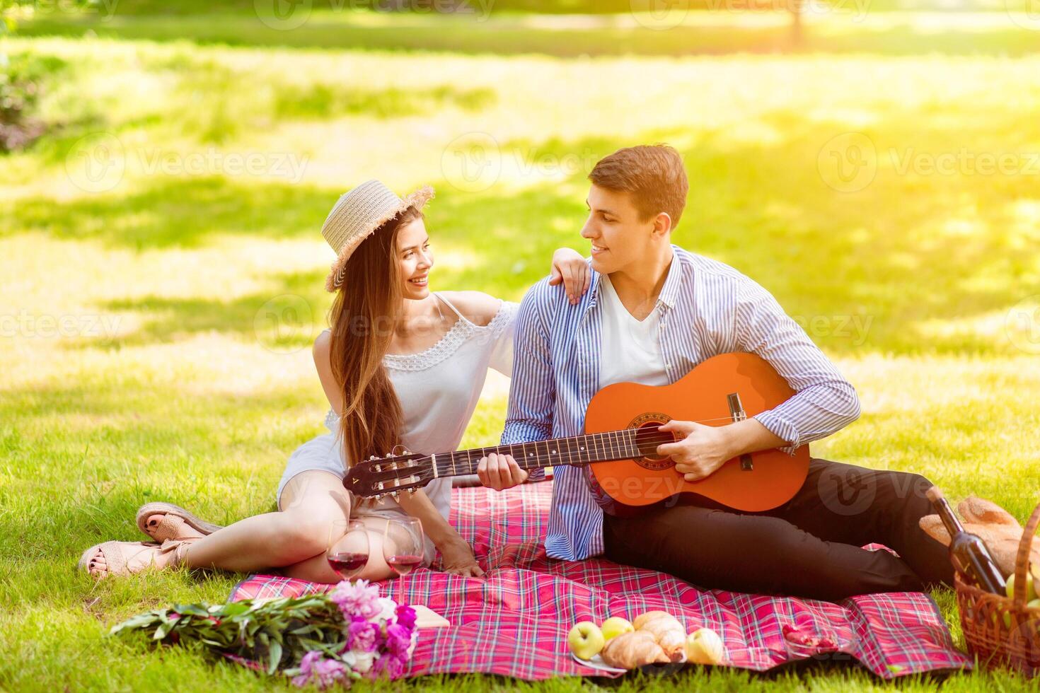 Handsome young man singing romantic song to his beloved girl on summer picnic at park photo