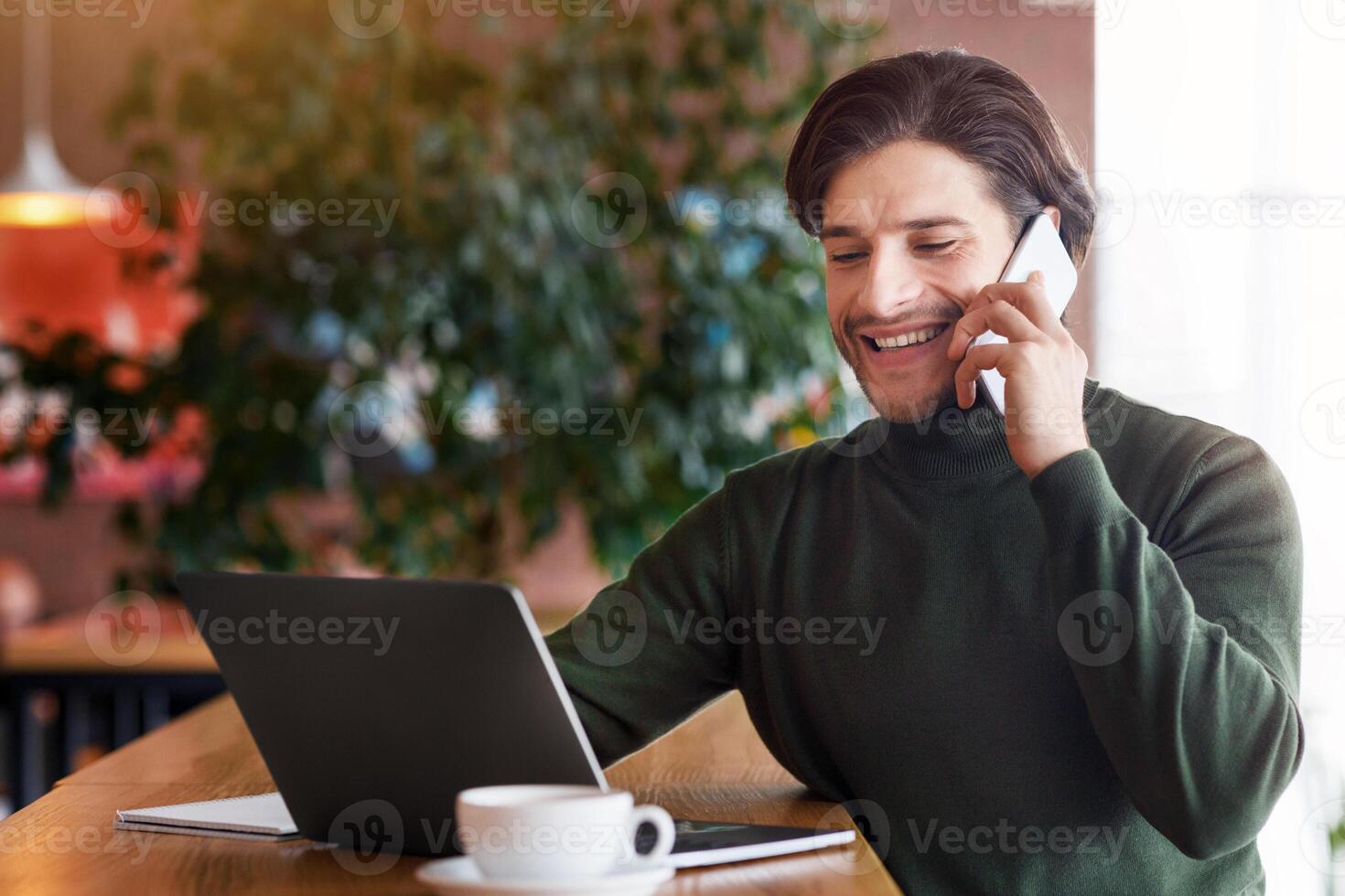 Successful entrepreneur having conversation on smartphone while working with laptop at cafe, copy space photo