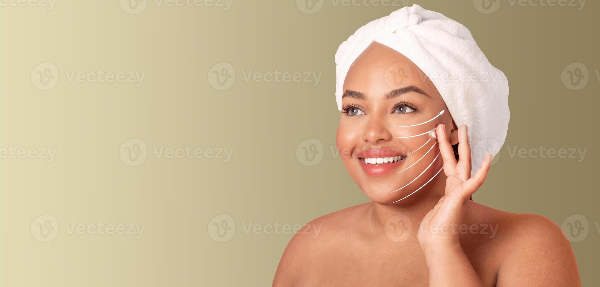 A woman relaxed and smiling while applying a facial massage technique at home. She is using a gentle touch to promote skin care and anti-aging benefits, copy space photo