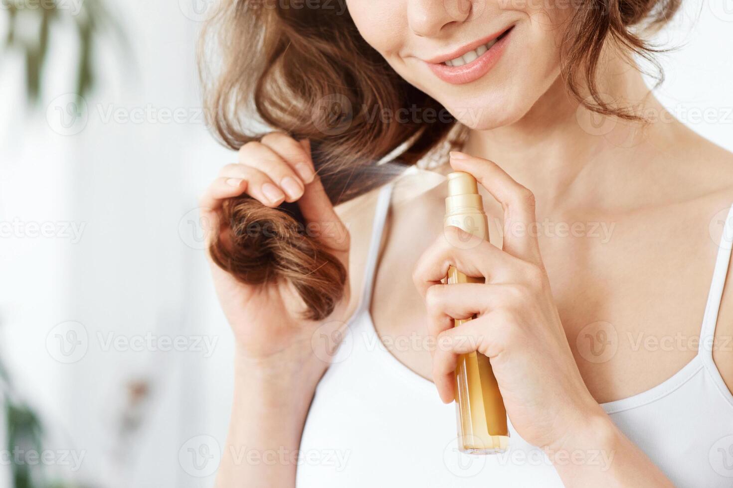 Pretty blonde girl applying hair oil to prevent split ends, hair care at home concept, copy space, sun flare photo