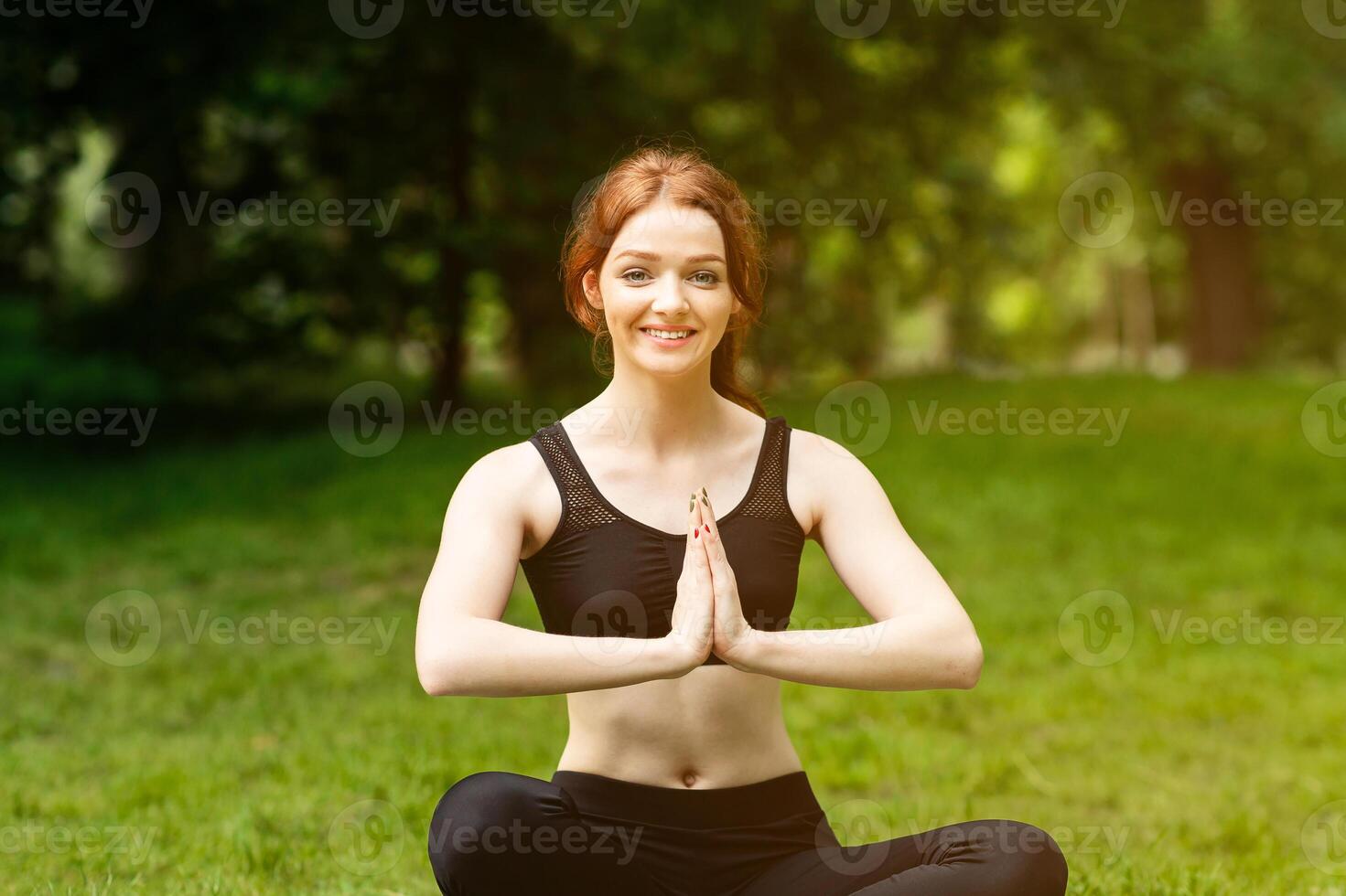 Cheerful Caucasian woman making namaste gesture during her outdoor yoga meditation. Panorama photo