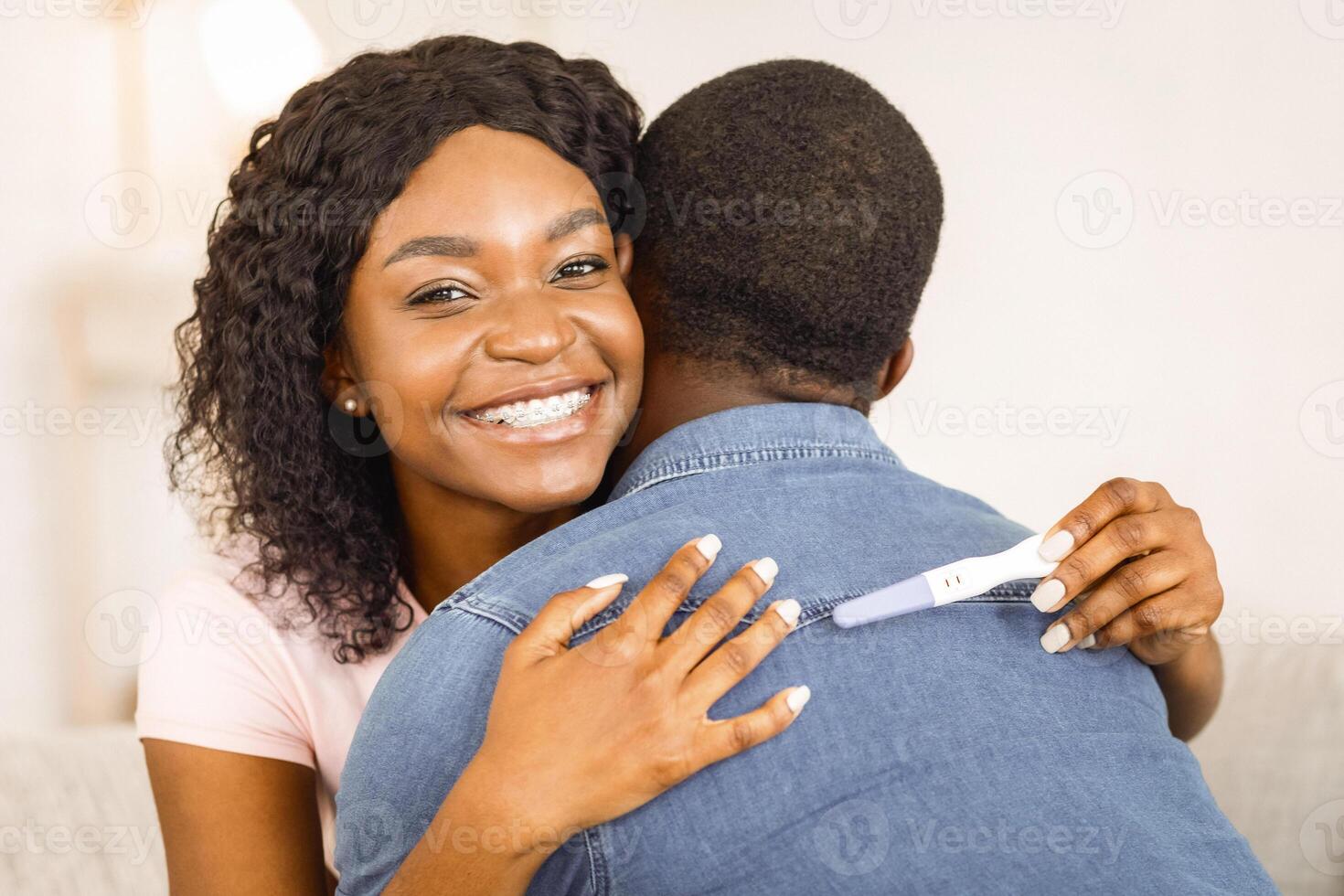 Black girl with pregnancy test hugging her boyfriend, happy to become parents, copy space photo