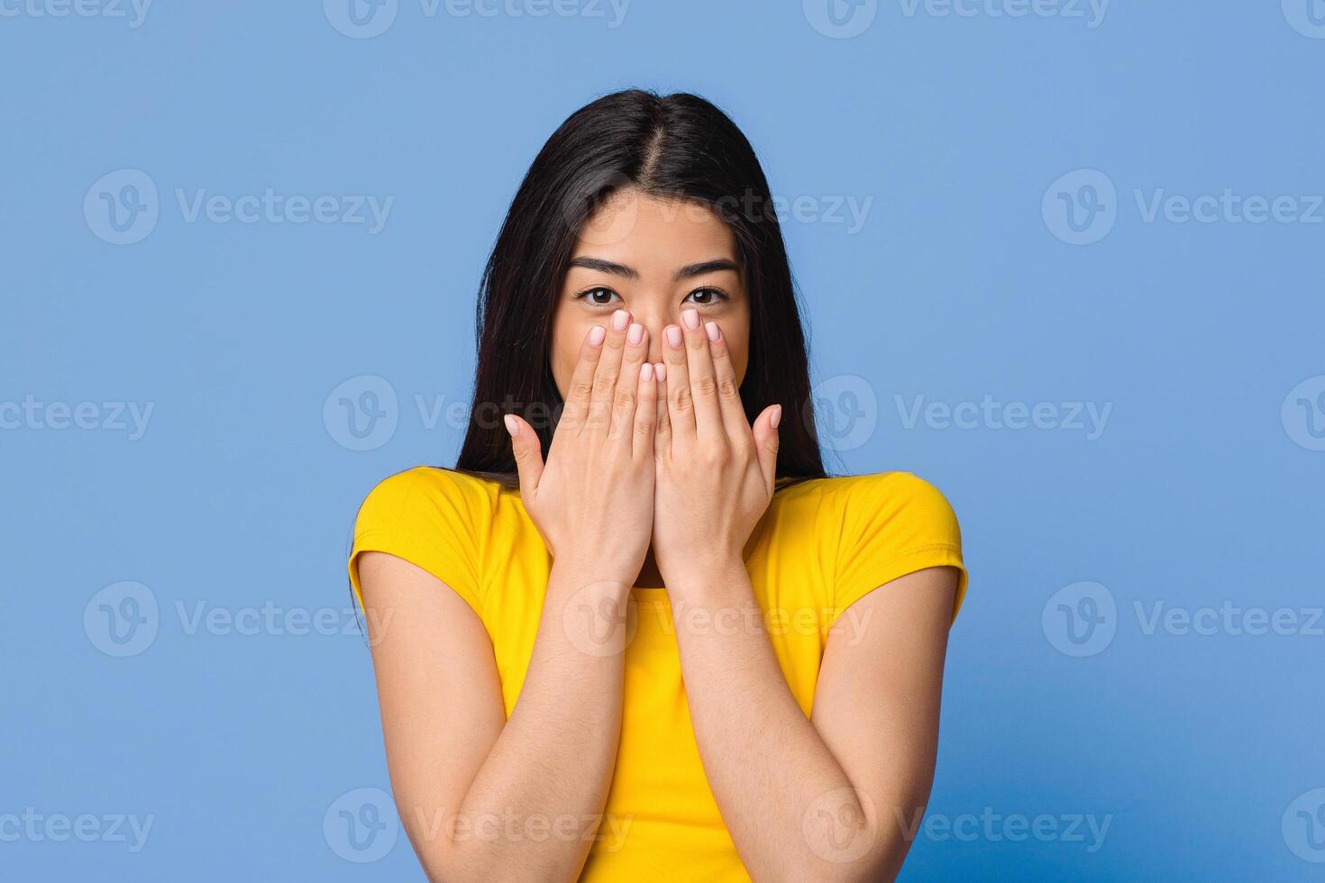 Happy Excitement. Shy Asian Woman Covering Mouth With Hands, Emotionally Reacting To Pleasant Surprize, Giving Positive Reaction, Looking At Camera, Standing Over Purple Studio Background, Free Space photo