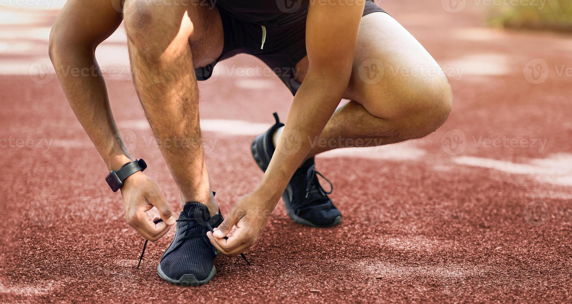 Close up view of black jogger tying laces on his sports shoes during his training outside. Panorama photo