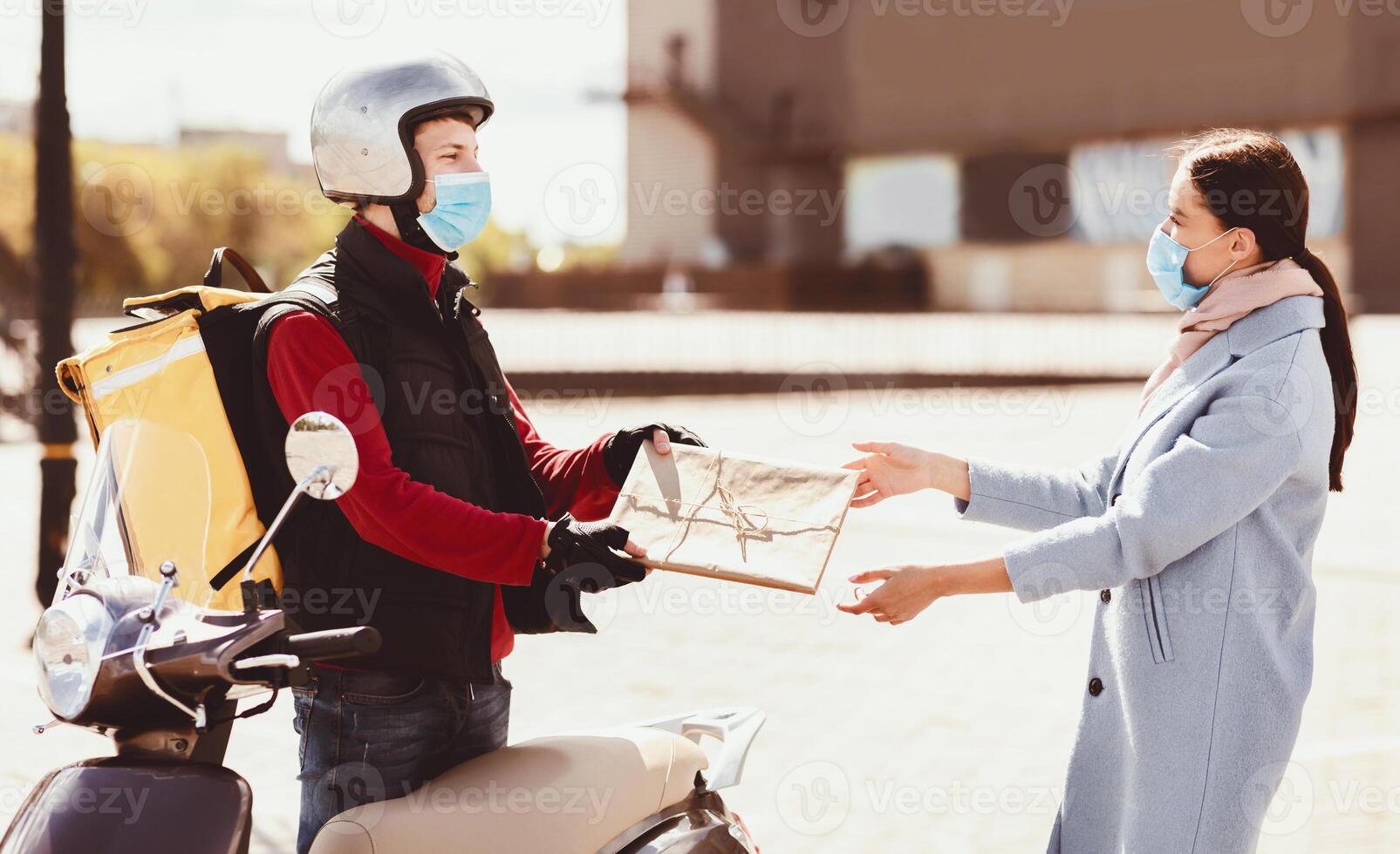 Safe Delivery Service. Courier In Protective Mask Delivering Package To Customer Standing With Scooter In Urban Area Outdoor. photo