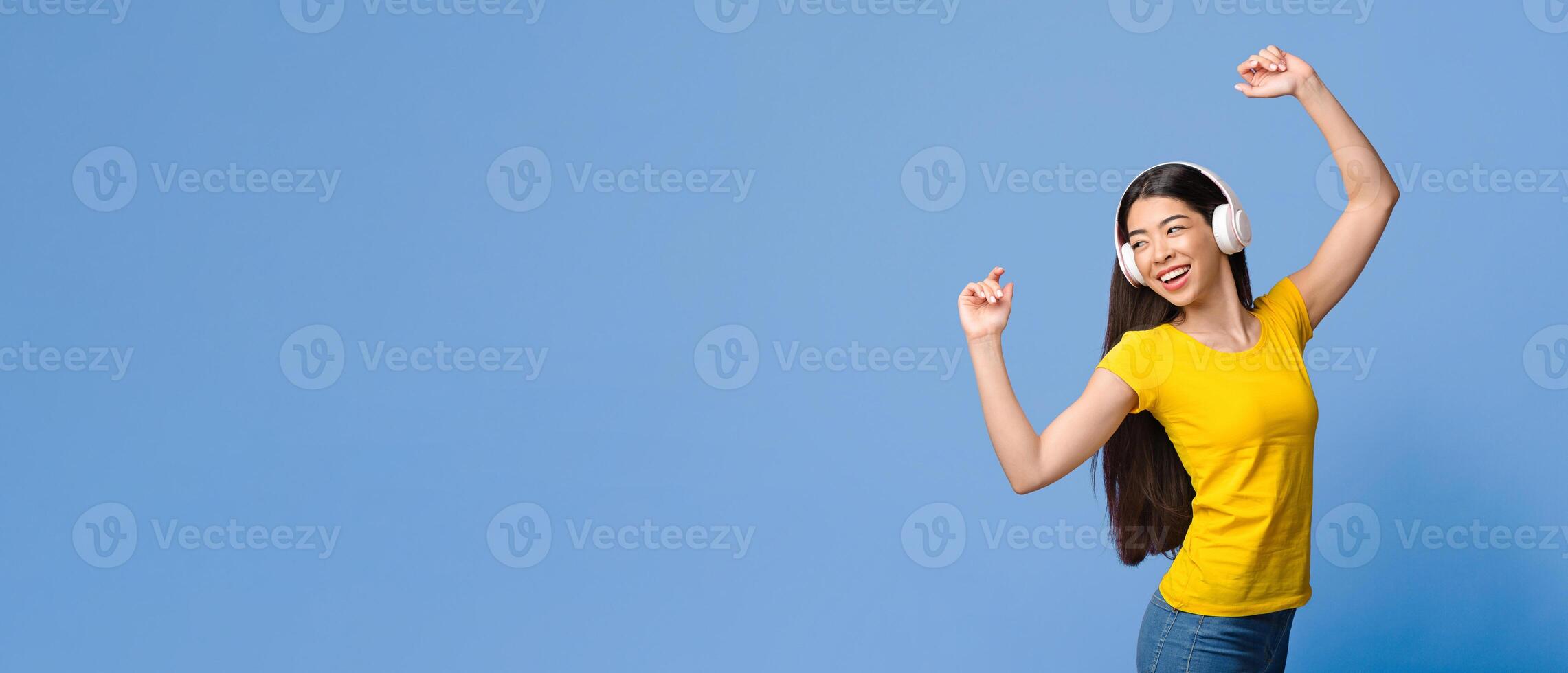 Joyful Korean Girl Dancing While Listening Music In Wireless Headphones, Standing Over Purple Studio Background, Panorama With Copy Space photo