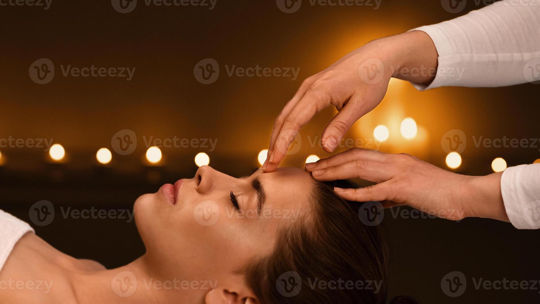 Tranquil girl getting head massage in romantic atmosphere at spa salon, side view photo