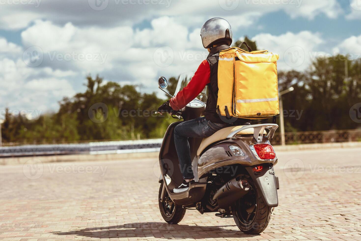 Food Delivery Service. Courier With Yellow Backpack Riding Scooter Delivering Restaurants Meals In City Outside. Back View, Empty Space photo