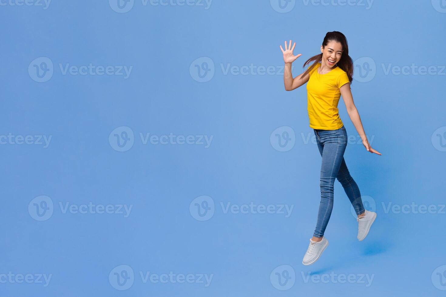 Joy Of Youth. Cheerful Asian Girl Jumping In The Air Over Purple Studio Background, Full-Length Shot With Copy Space photo