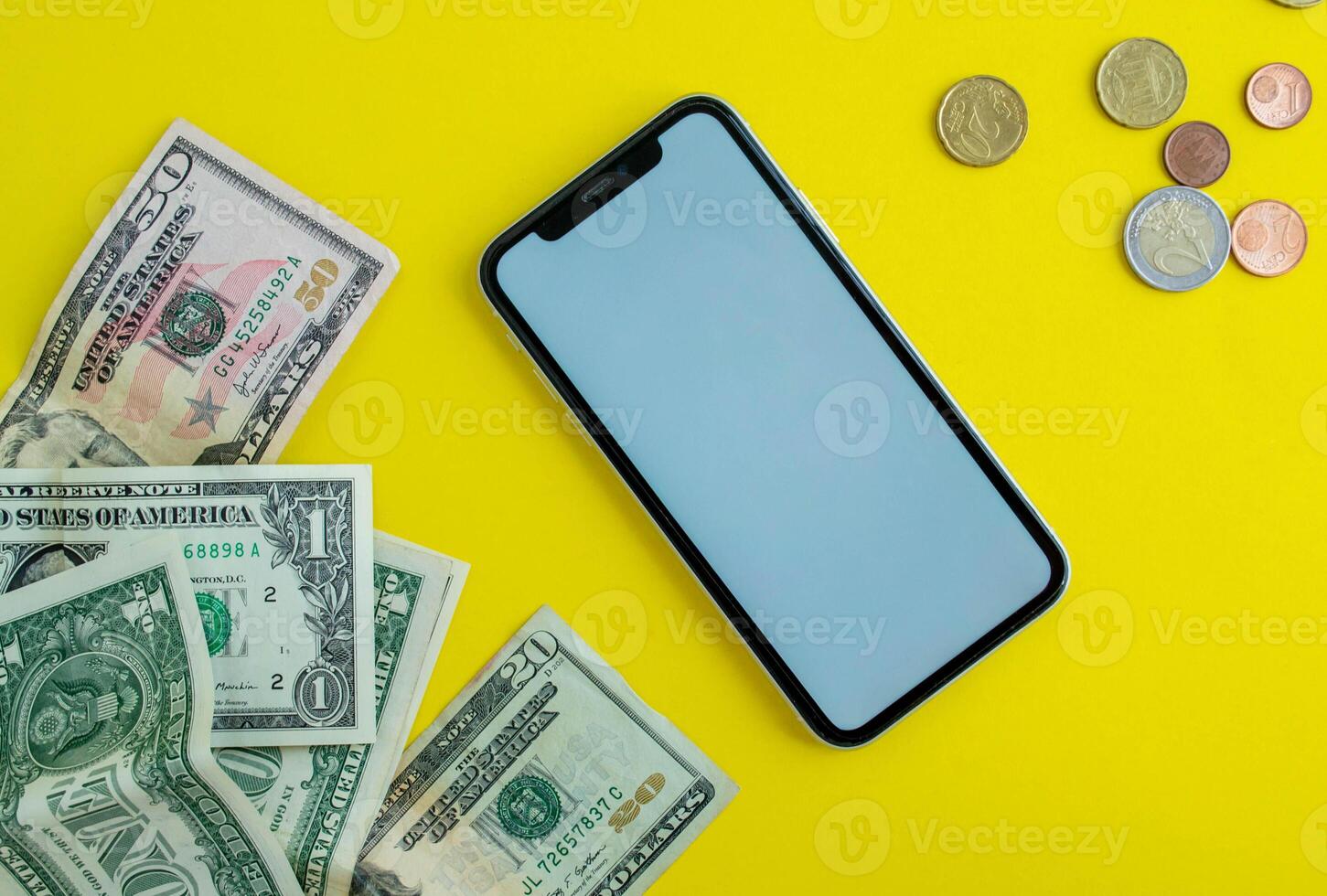 Mockup, smartphone, dollars and euro coins on a yellow background. photo