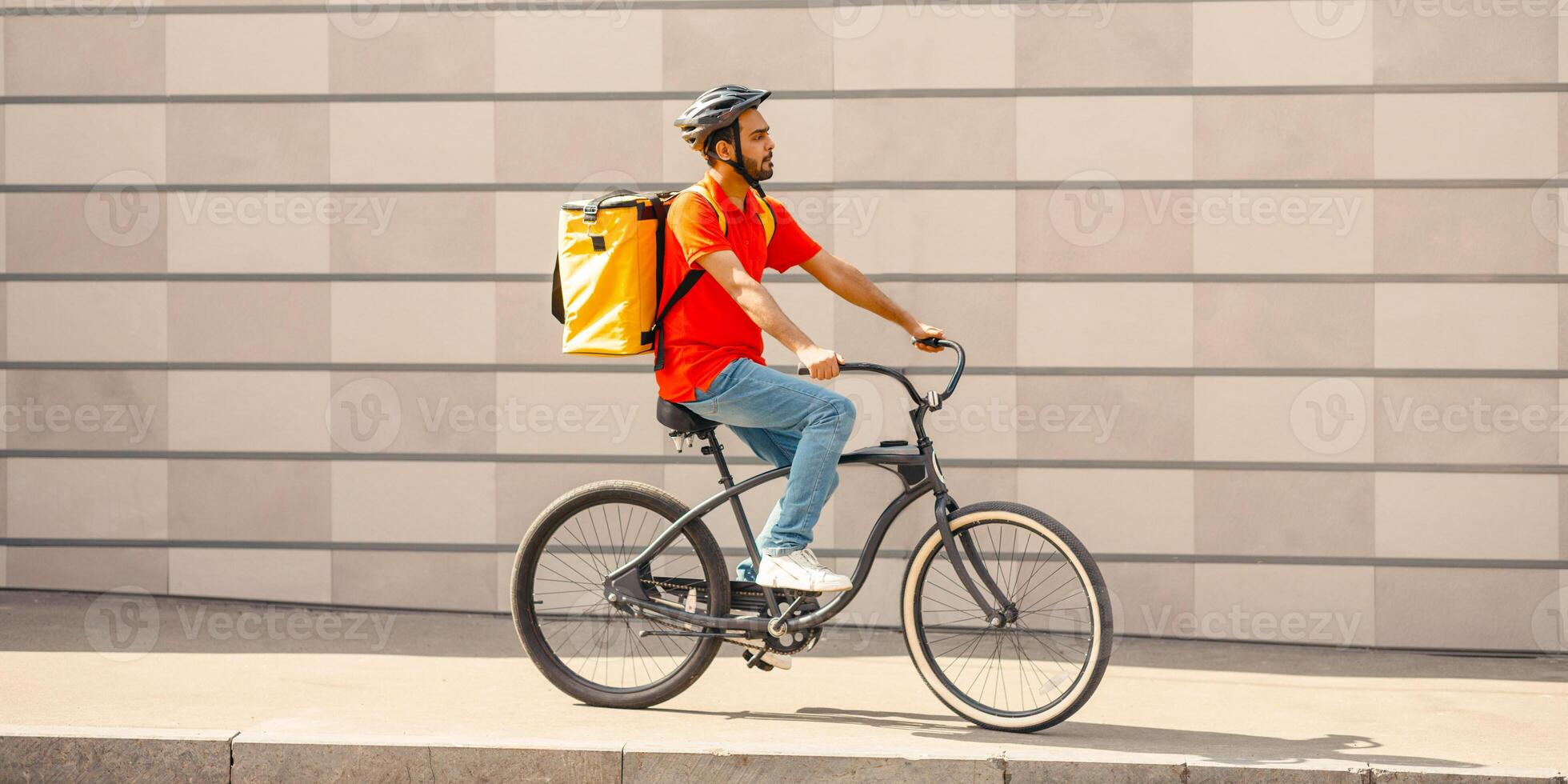 Eco-city and delivery. Young caucasian man cyclist in protective helmet with backpack riding bicycle on sidewalk with backpack in city, profile, copy space photo