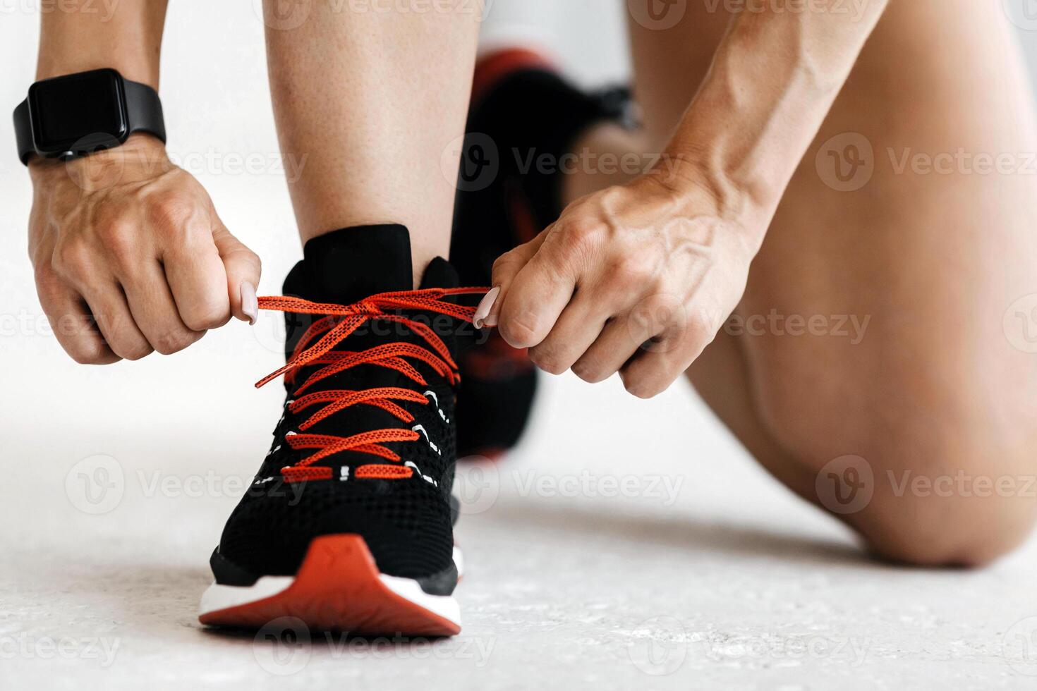 Fitness lifestyle. Muscular woman with smart watch tying shoelaces on sneakers on gym or living room, cropped, close up, panorama photo