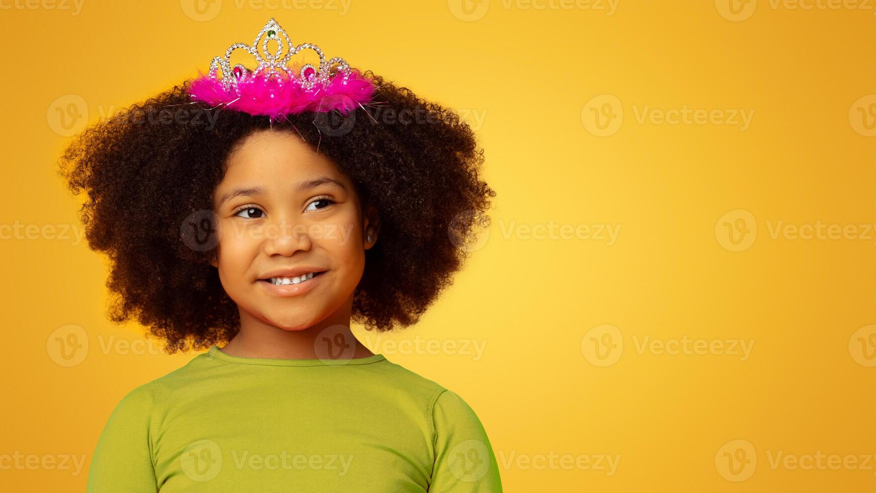 Charming little african american girl wearing princess crown and smiling, yellow background with free space photo