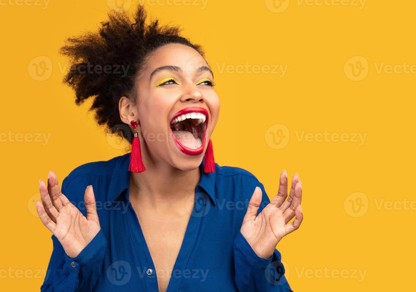 So Happy. Overjoyed black girl screaming isolated over yellow studio wall, looking away, copyspace photo