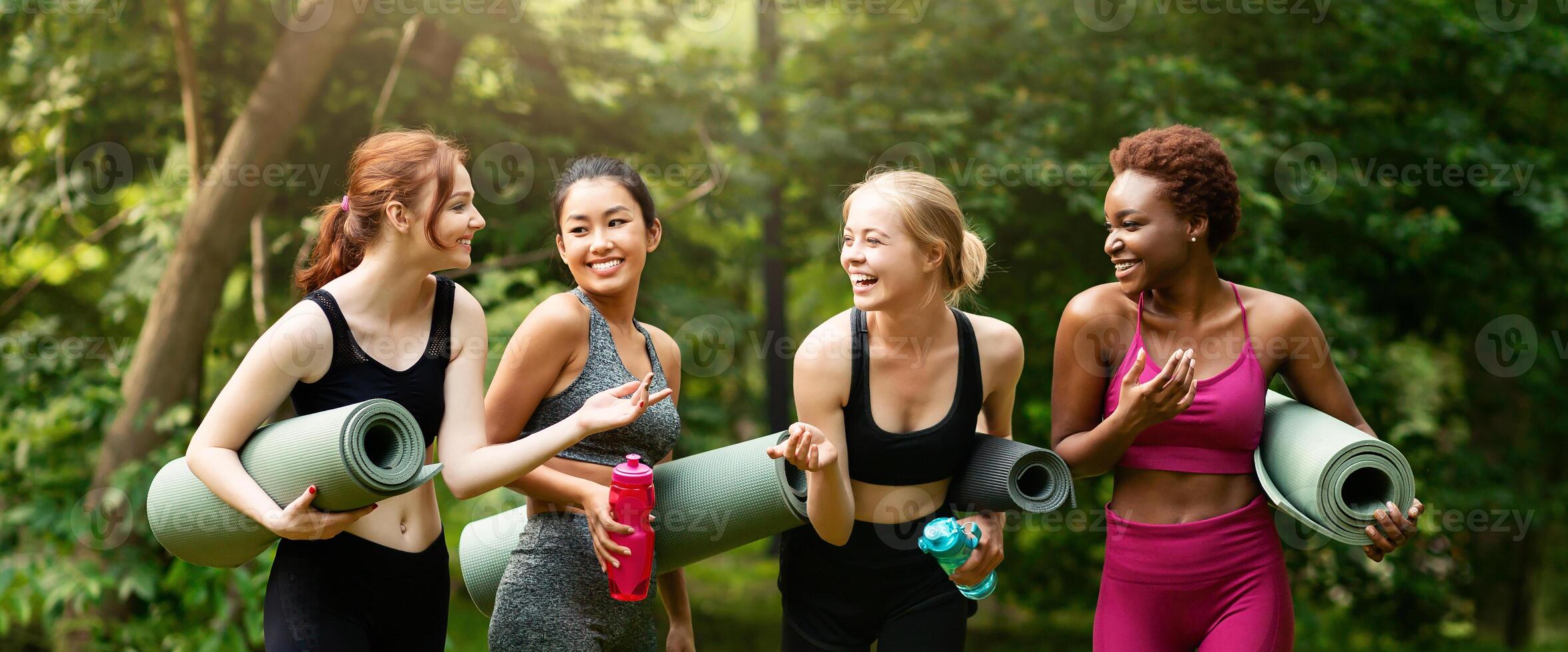 Group of millennial girls communicating before their yoga practice in nature, panorama photo