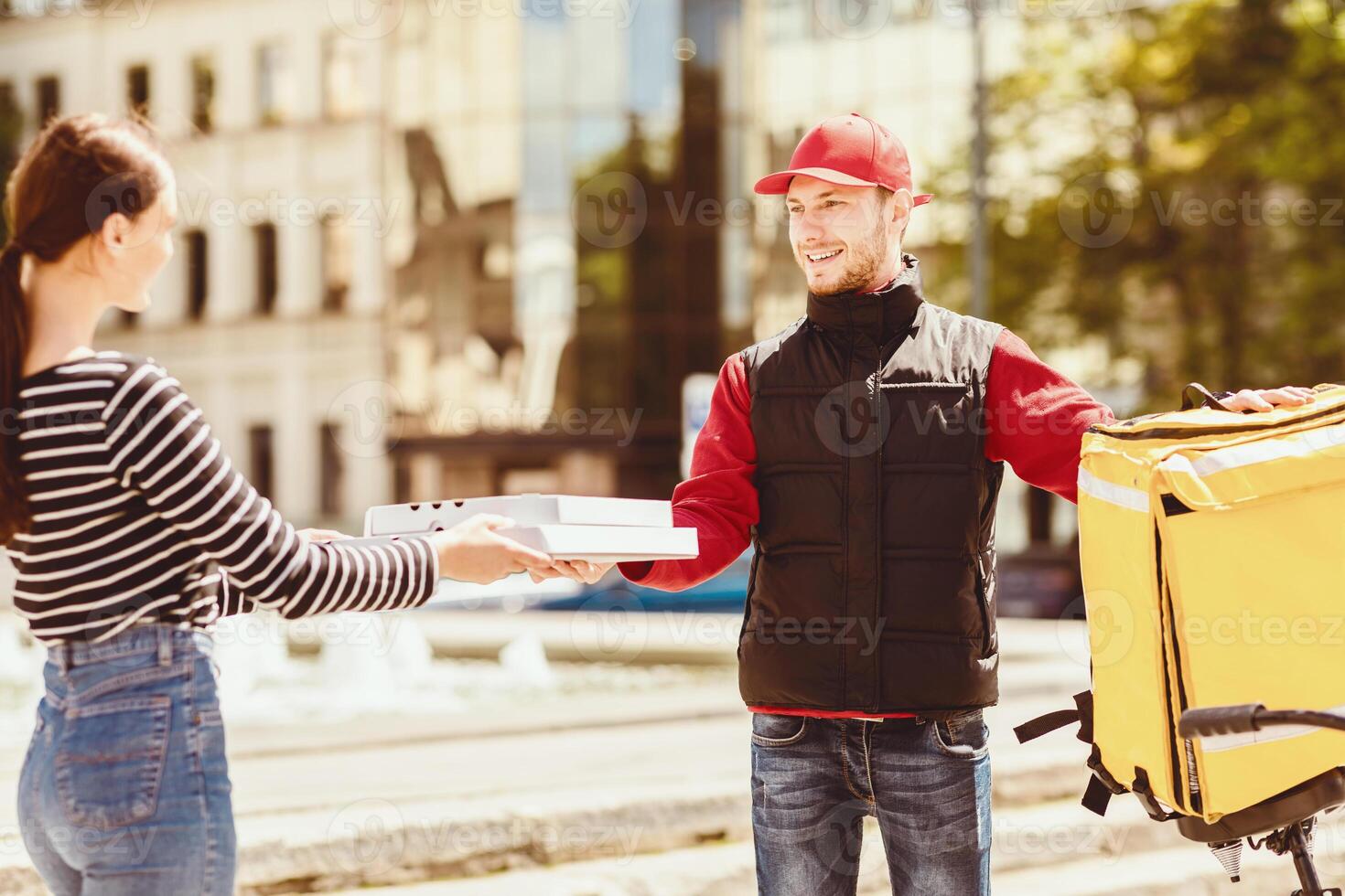 Courier Giving Pizzas Boxes To Girl Delivering Food From Pizzeria Standing Outside. Selective Focus photo