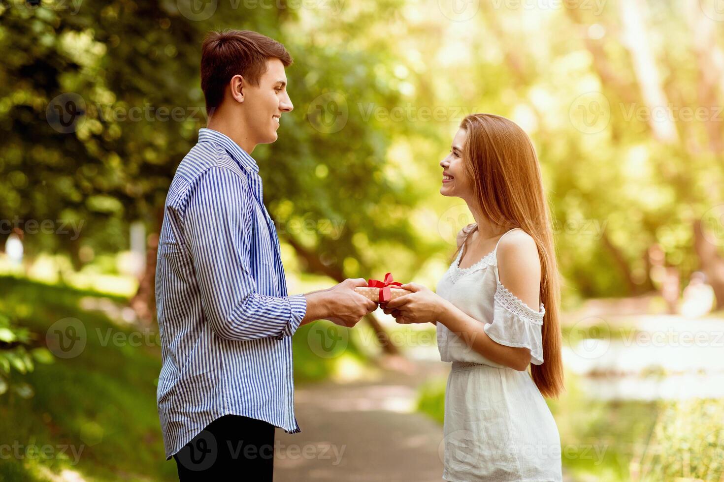 Romantic boyfriend giving birthday present to his beautiful girlfriend at green park photo