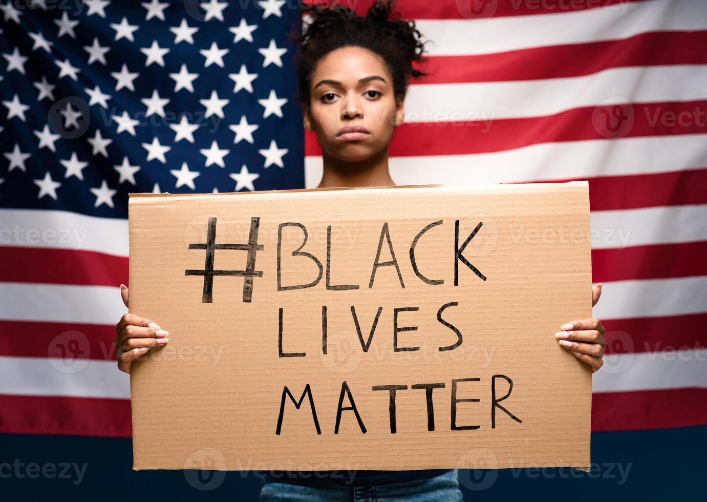 Mass ptotests in USA. Black girl standing with blank cardboard over american flag photo