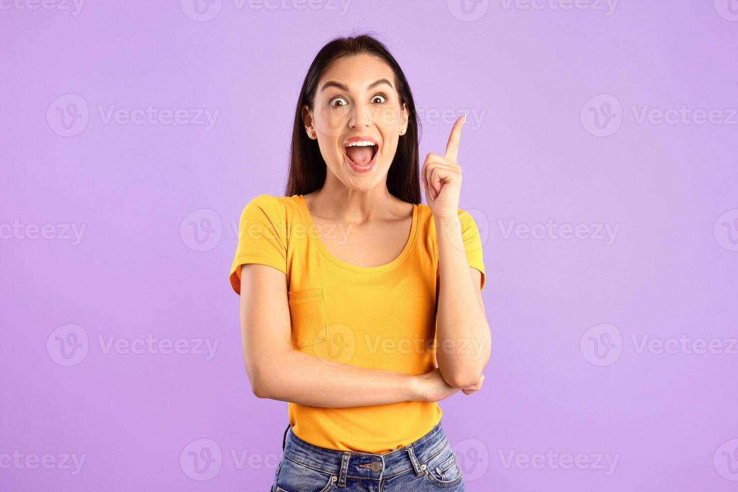 Wow, Eureka. Portrait of emotional woman having great idea, finding inspiration or solution to problem. Excited amazed lady with open mouth pointing finger up isolated over purple studio background photo