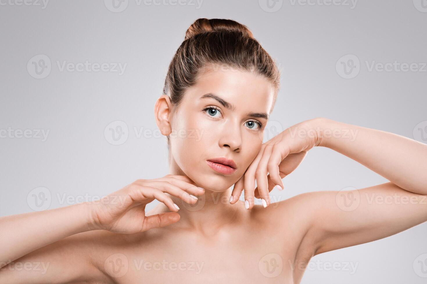 Sensual young woman posing over grey background, touching her face, female beauty concept photo