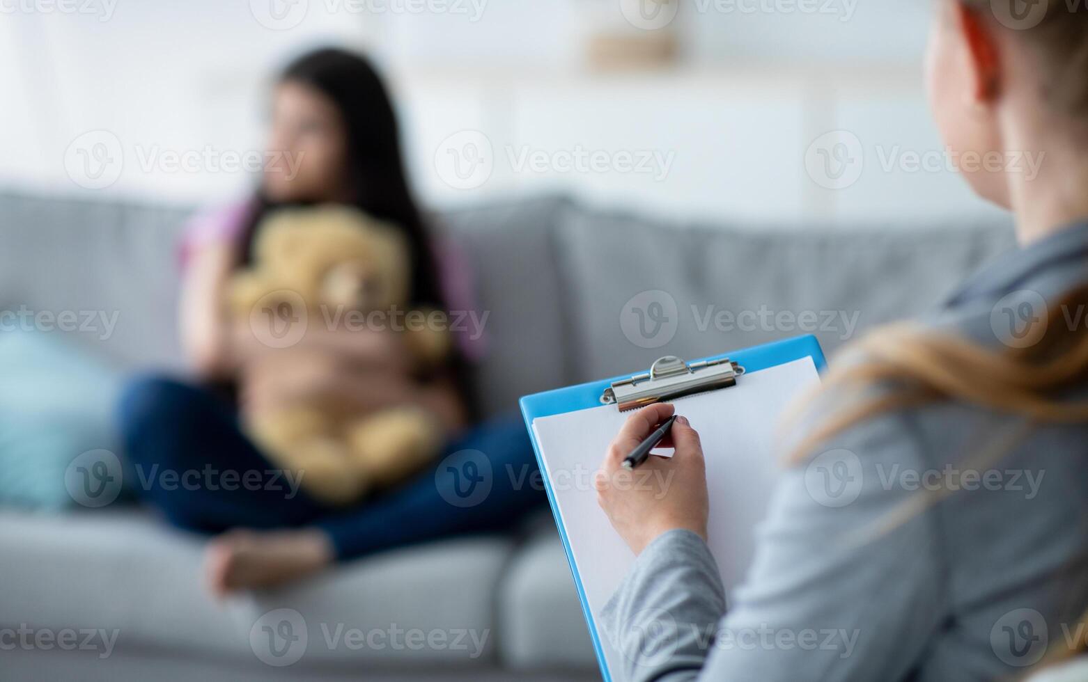 Teenage depression. Psychologist working with upset teen girl at office, talking to her patient, taking notes, selective focus. Unhappy adolescent having consultation with psychotherapist, copy space photo
