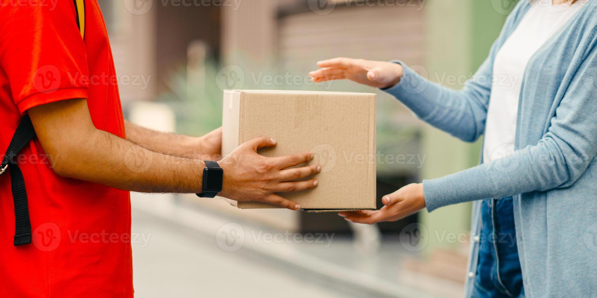 Quarantine and online delivery service. Woman in casual takes on parcel from courier with smart watch and yellow backpack, cropped, side view, panorama, free space photo