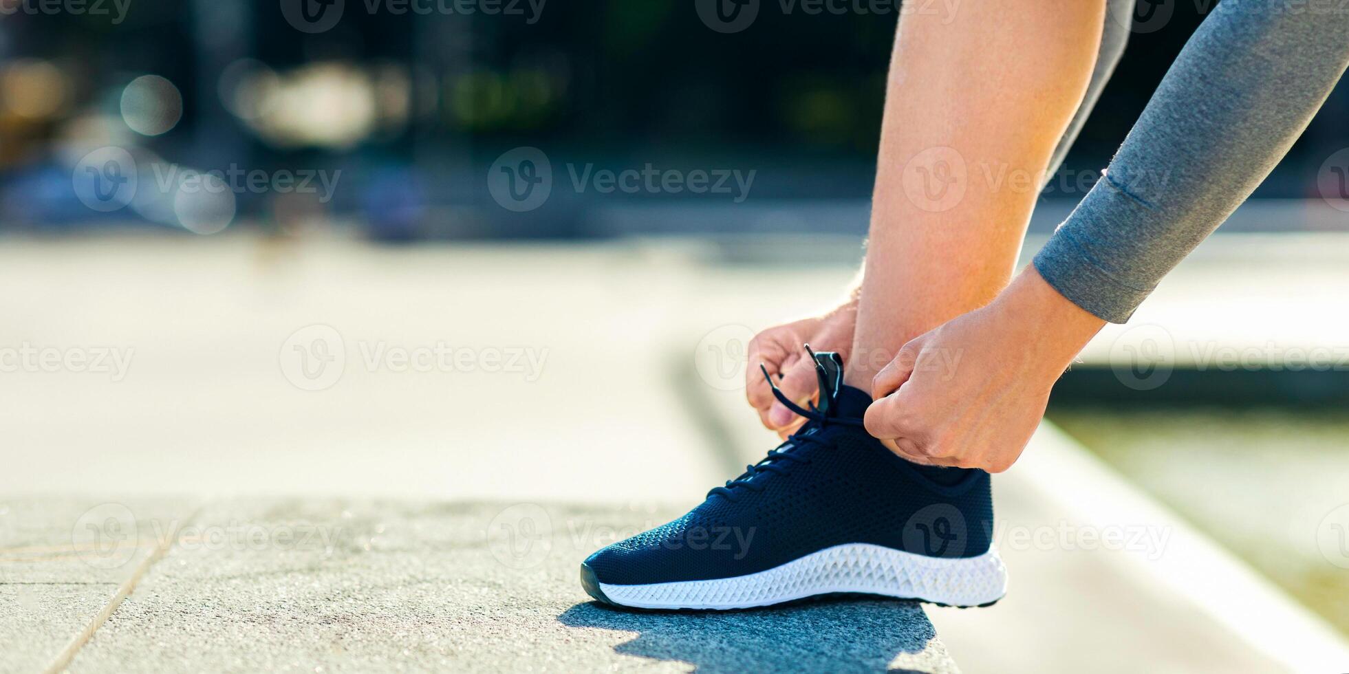 Morning starts with run. Guy ties laces on his sneakers on street, cropped, close up, free space photo