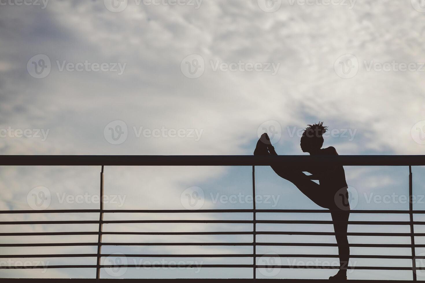 Stretching outdoors. Silhouette of african american woman athlete, doing exercise at stadium on blue sky with clouds background, free space photo