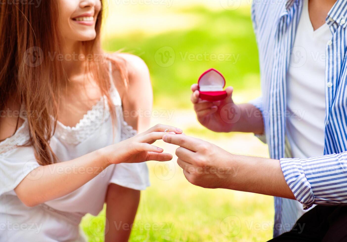 Summer proposal. Affectionate guy putting engagement ring on woman's finger in countryside photo