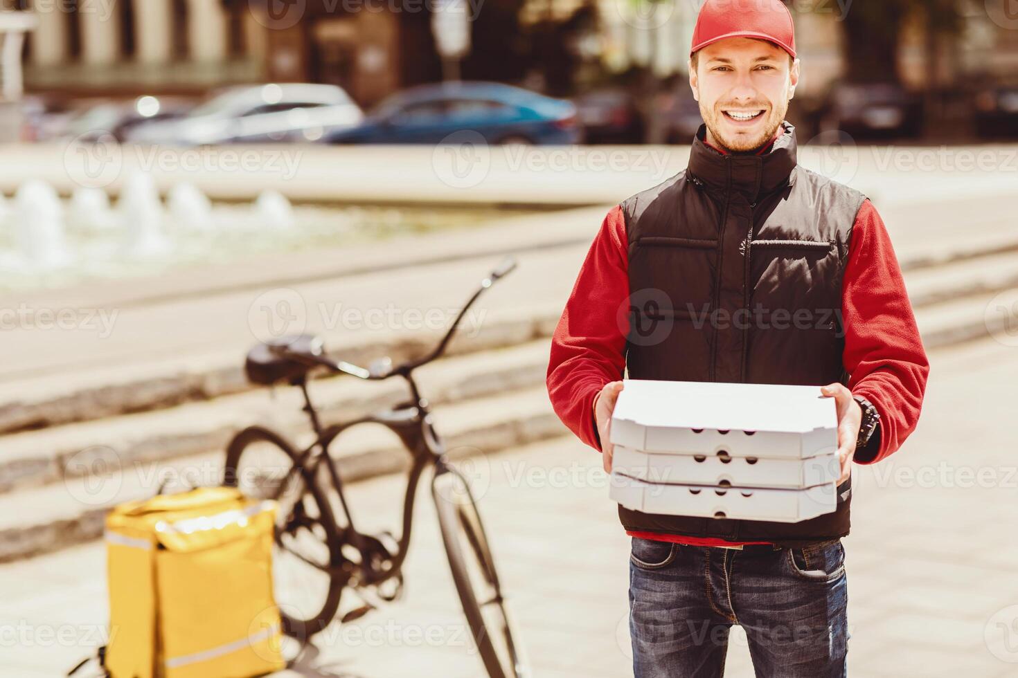 Pizzeria Delivery. Courier Holding Pizza Boxes Smiling To Camera Standing Near Bicycle In City Outside. Free Space photo