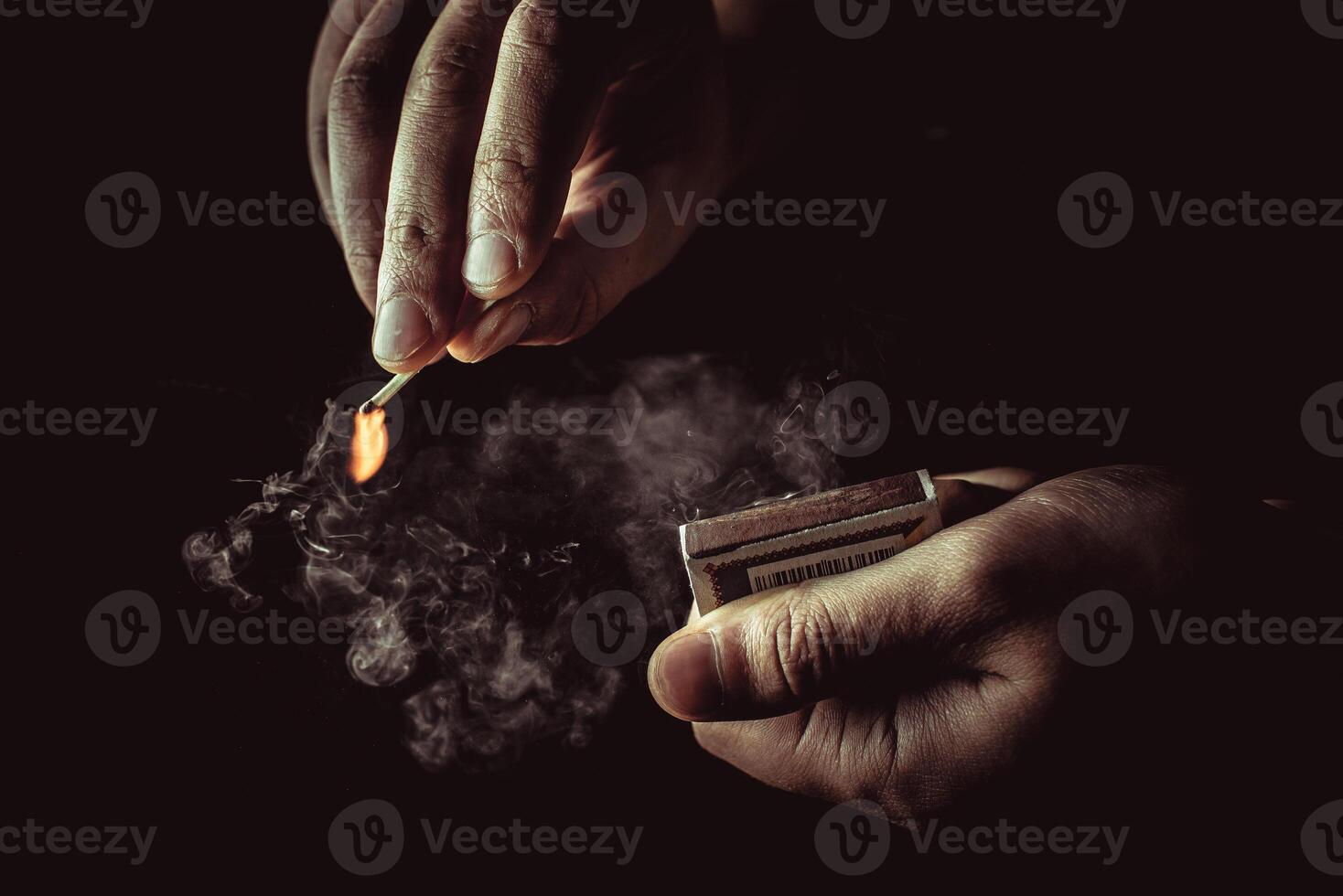 Playing with fire. A burning match in a man's hand on a black background. photo