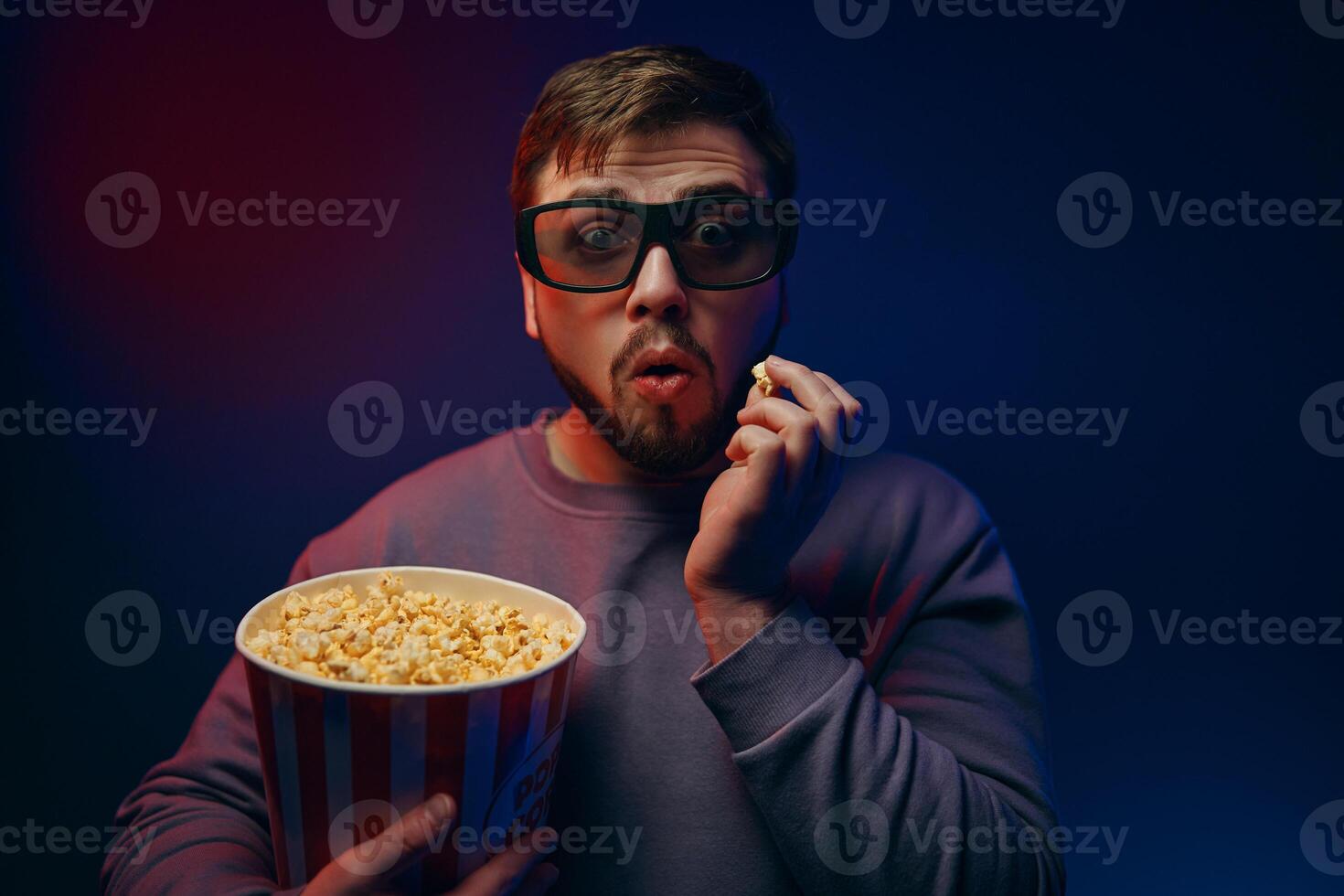 A man in 3D glasses and popcorn is watching a movie. photo